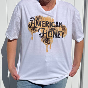 Indulge in the sweet charm of our captivating graphic tee featuring vibrant yellow honeycombs, a depiction of golden honey, and a quote that proudly exclaims, "American Honey."